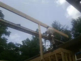 Carpenter setting a ridge beam over a new addition frame — Ice Dam Removal by Roofing Brothers in Almont